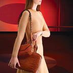 Woman holding a brown handbag against a red background