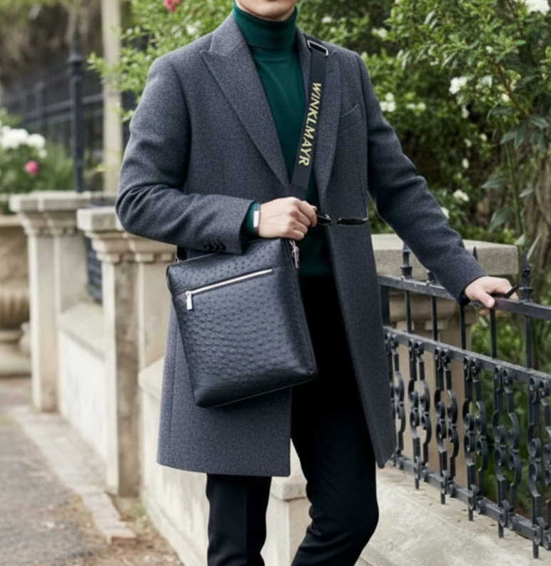 Man in a gray coat holding a black african ostrich quill leather bag