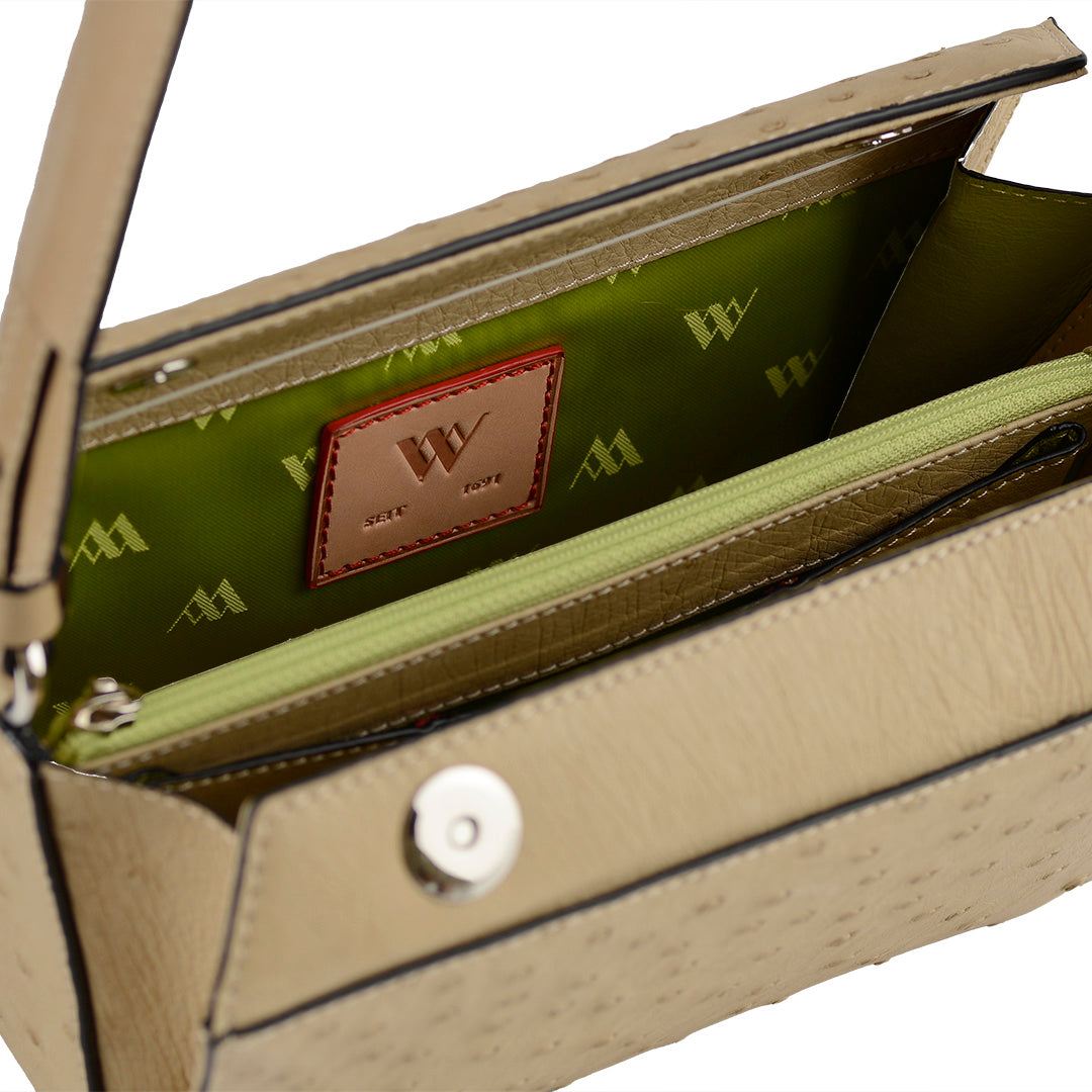 Close-up of a beige handbag with a green interior and visible brand logo.