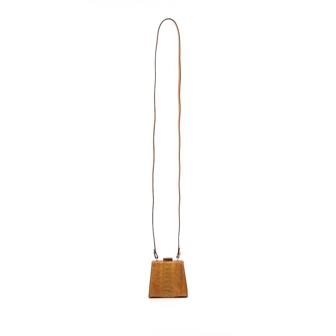 Wooden cowbell with a long leather strap on a white background