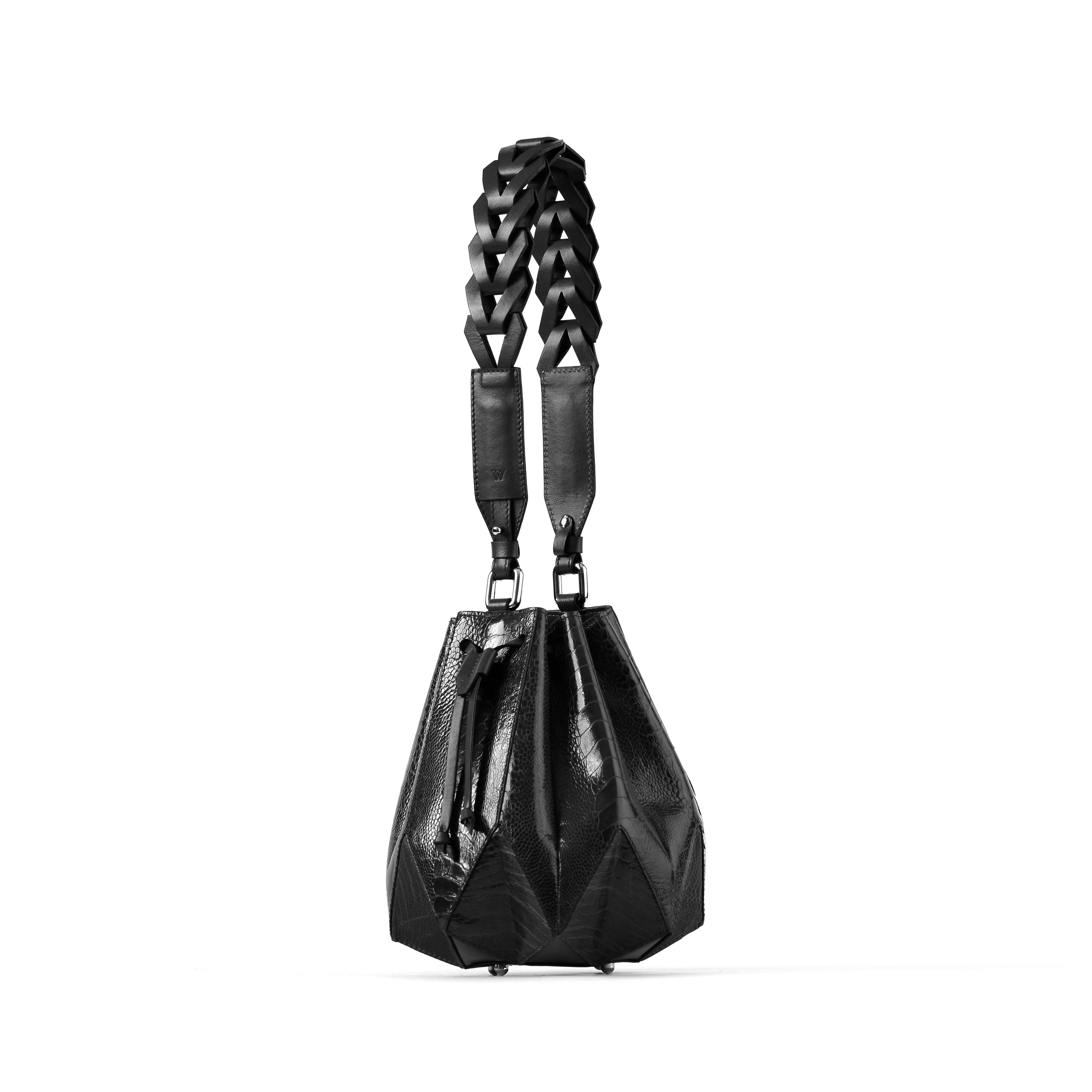 Black handbag with geometric design and braided handle on a white background
