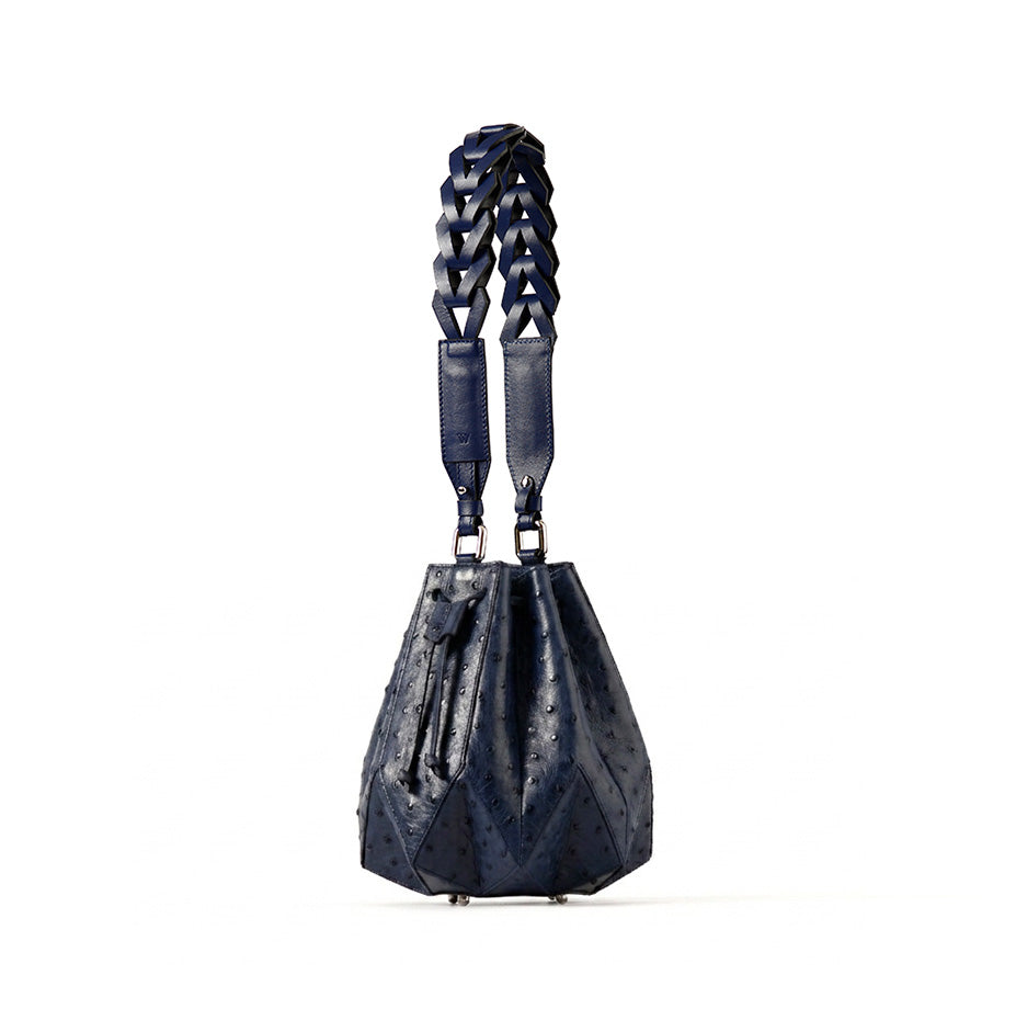 Blue handbag with braided handle on a white background