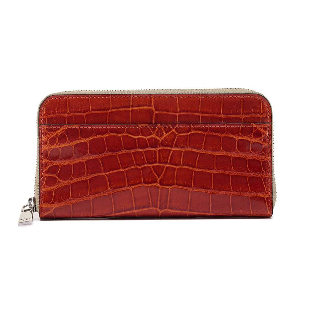 A cognac brown crocodile-patterned leather wallet with a zipper.