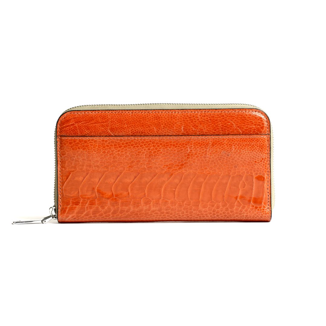An orange wallet with a textured ostrich leg leather surface and a zipper closure.