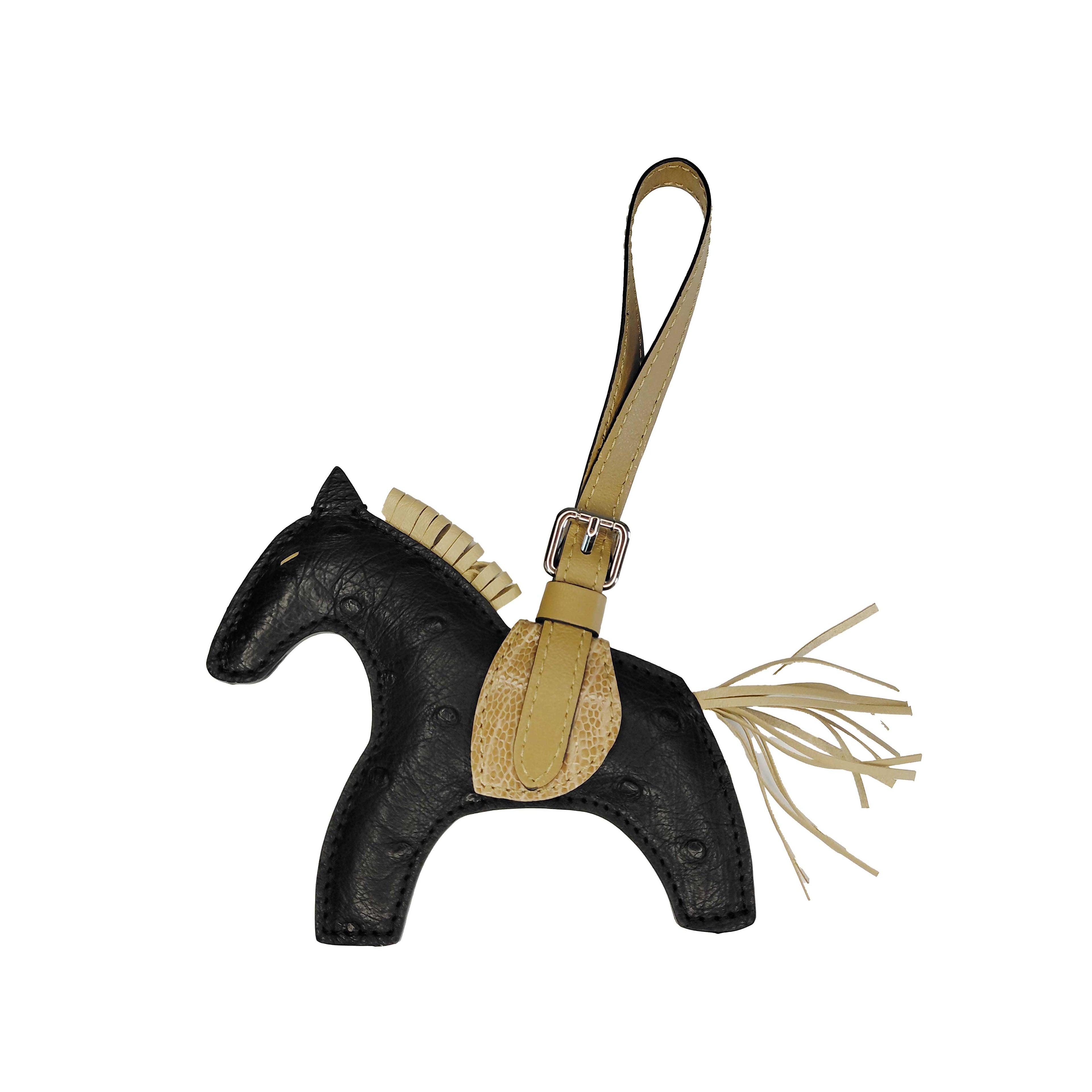 Horse-shaped keychain with black body and beige accents on a white background