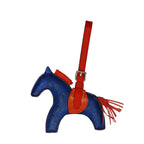 Blue horse-shaped bag with red strap and fringes on a white background
