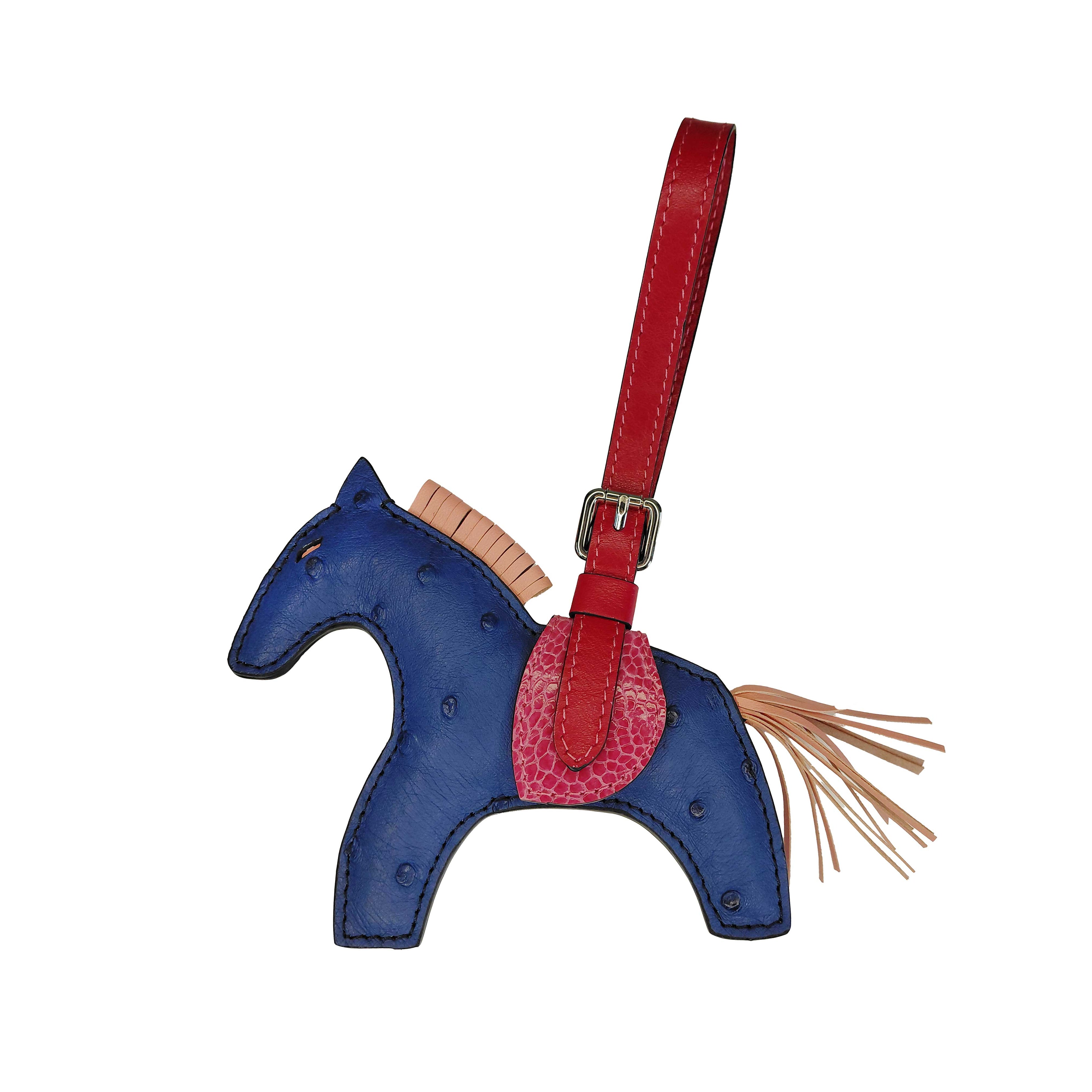 Blue horse-shaped keychain with a red strap on a white background