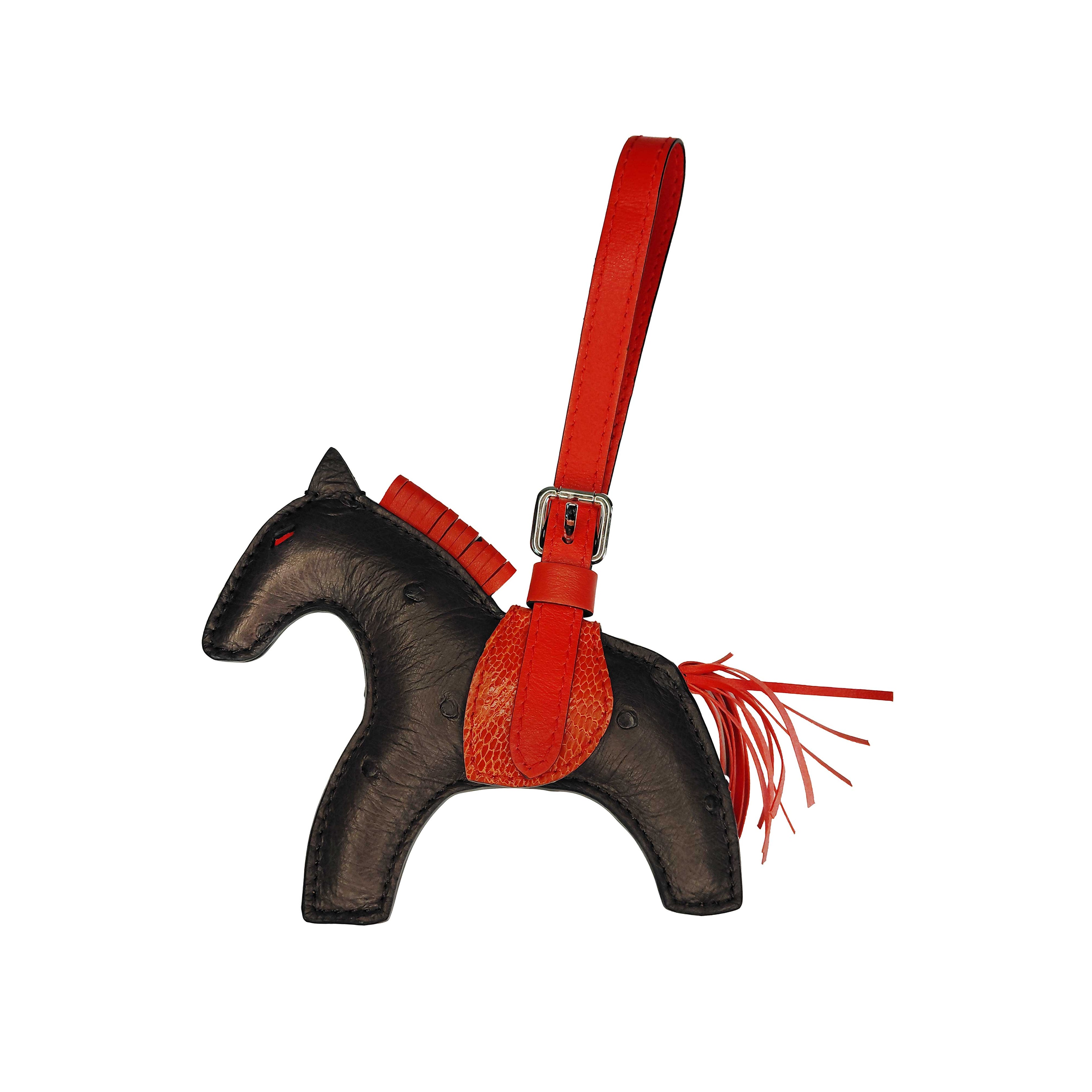 Horse-shaped keychain with red strap and fringes on a white background